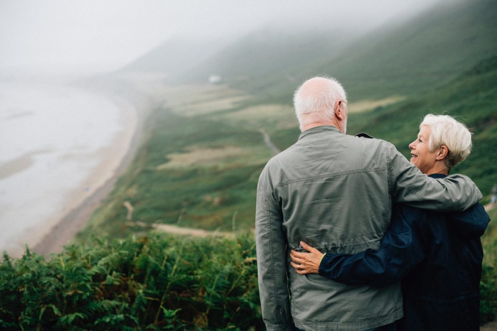Older man and woman standing on top of a hill looking at each other