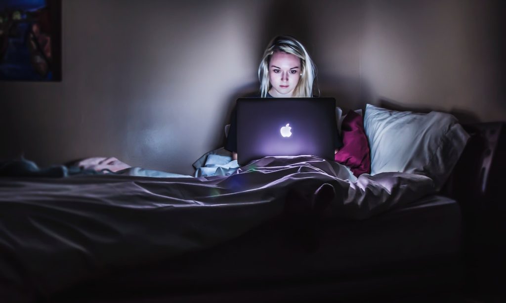 woman working in bed late at night what behaviours contribute to burnout