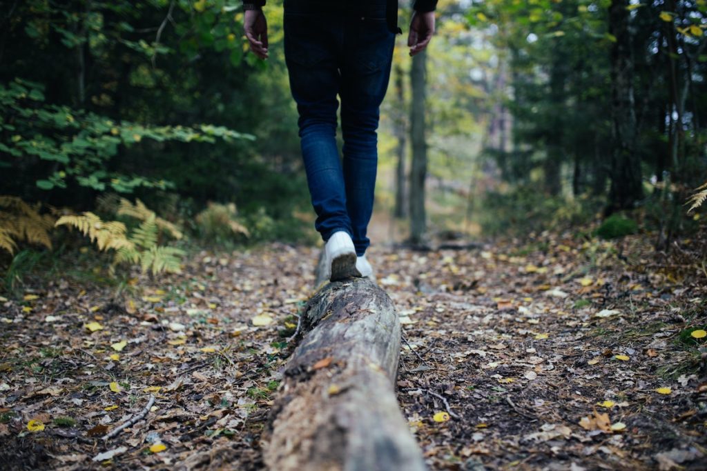Balance and coordination person walking on a log in the woods