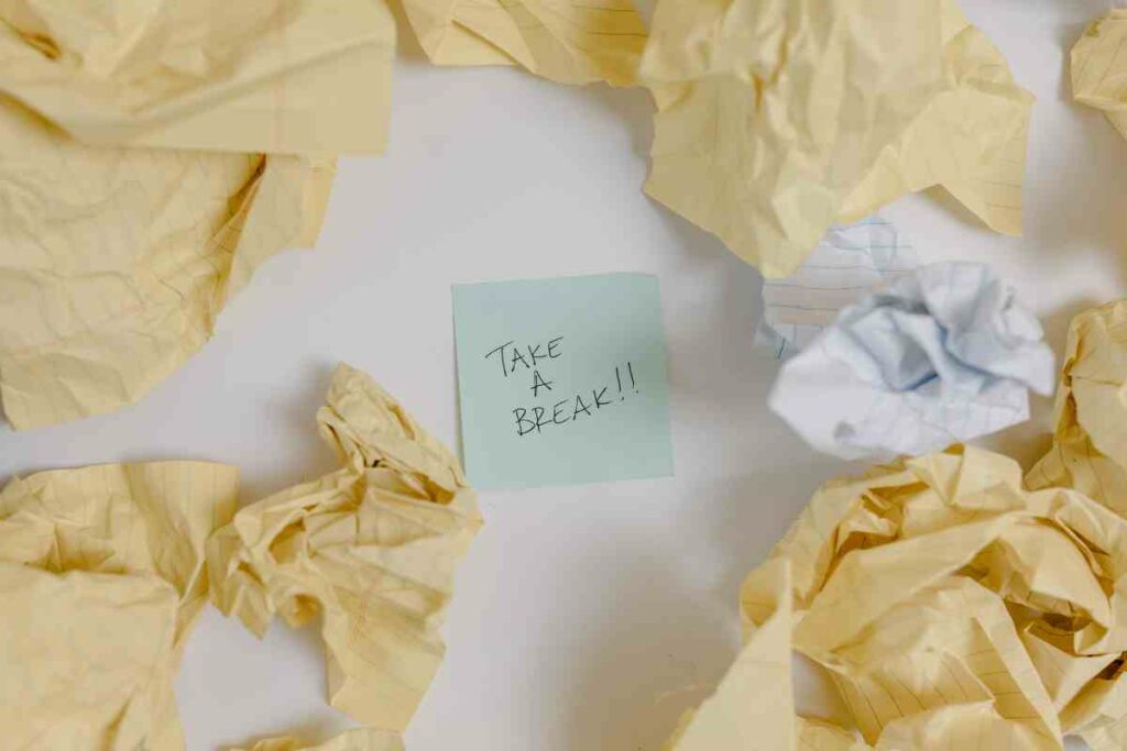Post-it note reading "take a break!!" amongst scrunched up pieces of paper. Taking breaks: advocating recovery in the workplace by Bodyshot Performance.