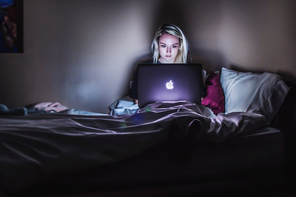woman working in bed late at night what behaviours contribute to burnout