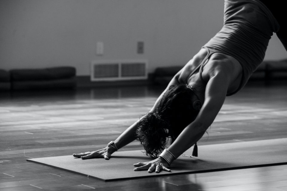 black and white photo of woman in downward dog yoga pose Yoga and mobility preventative health strategy