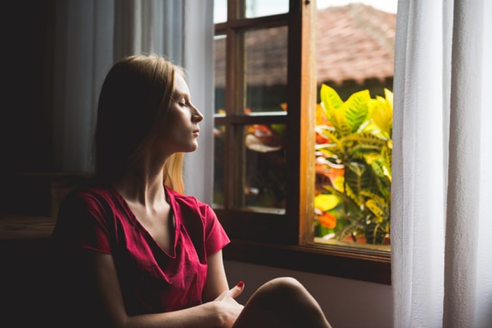 meditation for intrusive thoughts - woman staring out of window into nature.
