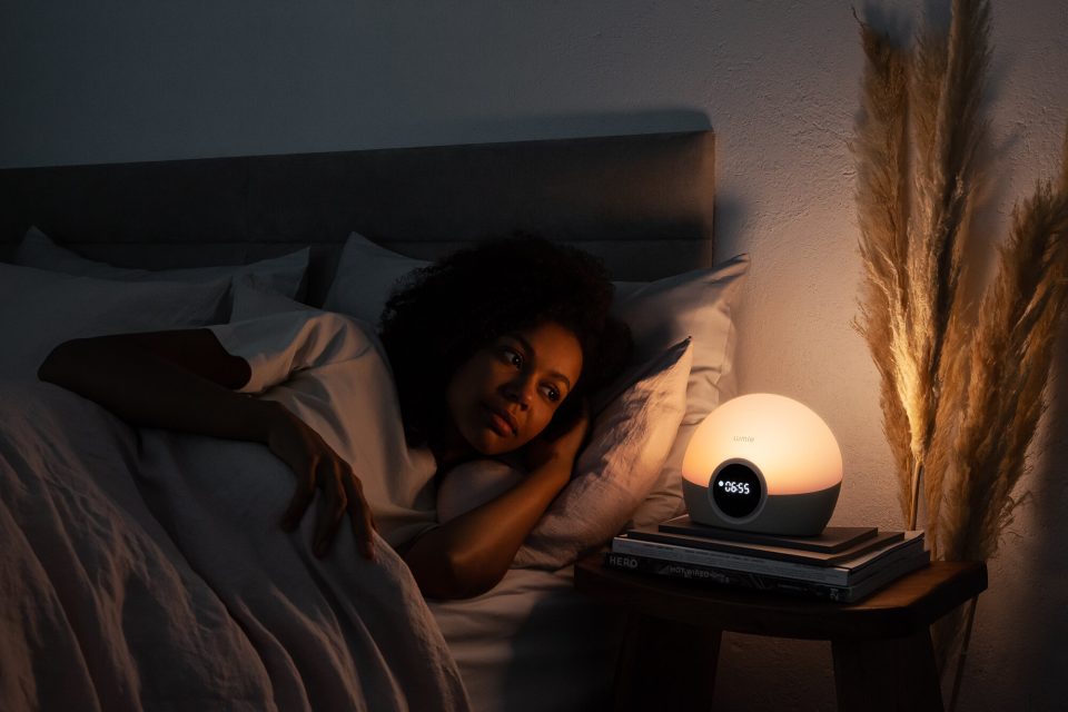 natural light exposure lumie lamp simulation - woman in bed with lumi lamp on the night stand