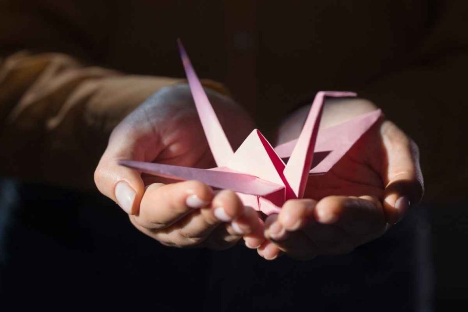 slivers of recovery: meditate. Person holds origami crane. Bodyshot Performance.